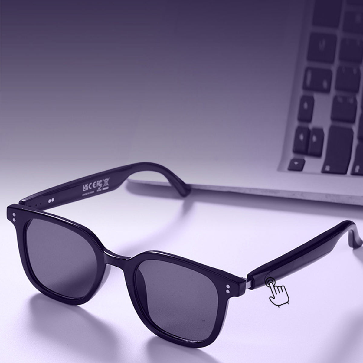VocaLens AI Smart Sunglasses with photochromic lenses Black sunglasses with a brand logo on a reflective surface in front of a laptop.