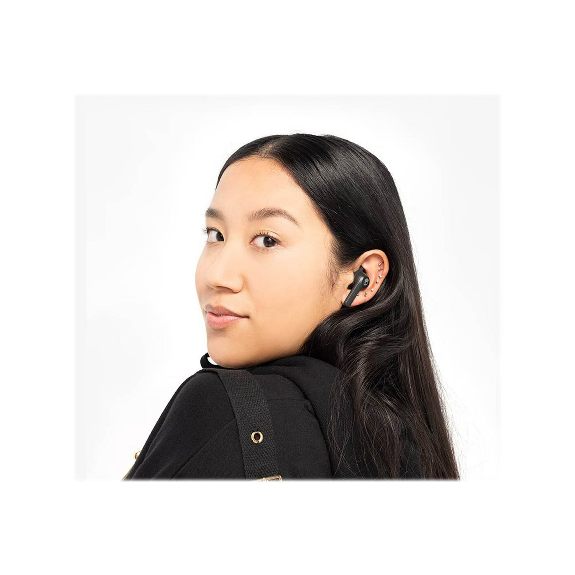 Woman wearing a black earbud with a plain white background with Skullcandy Indy Evo true wireless in-ear headphones in black