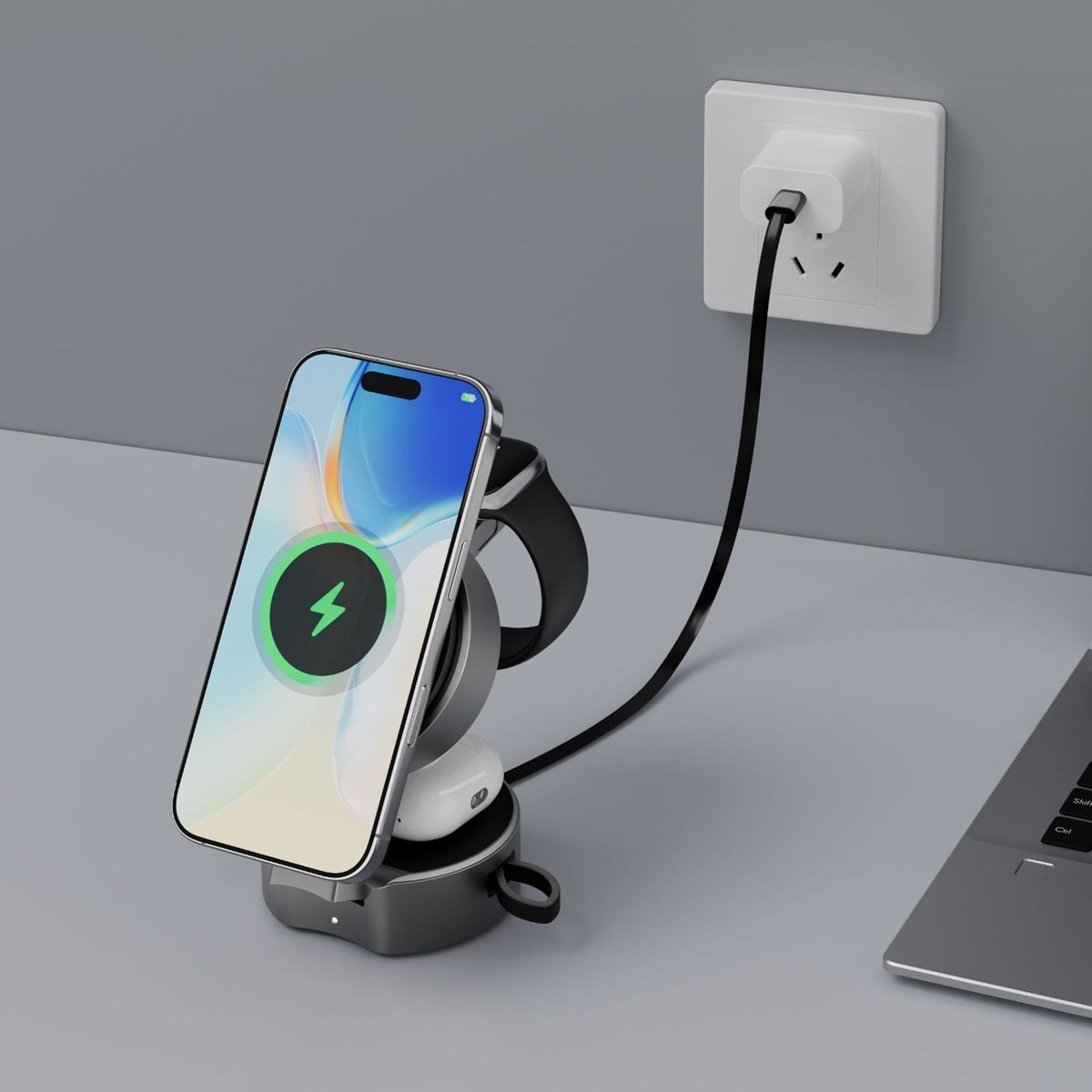 Smartphone on a wireless charging stand with a cable plugged into an outlet, on a gray surface.